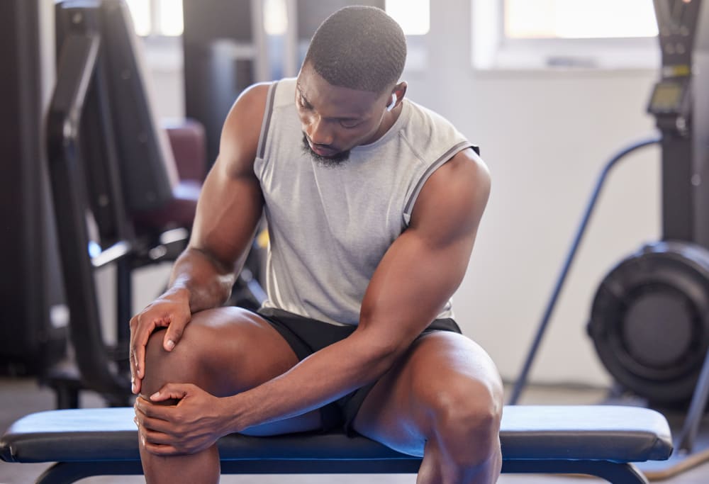 Man holding his knee in pain after a gym workout